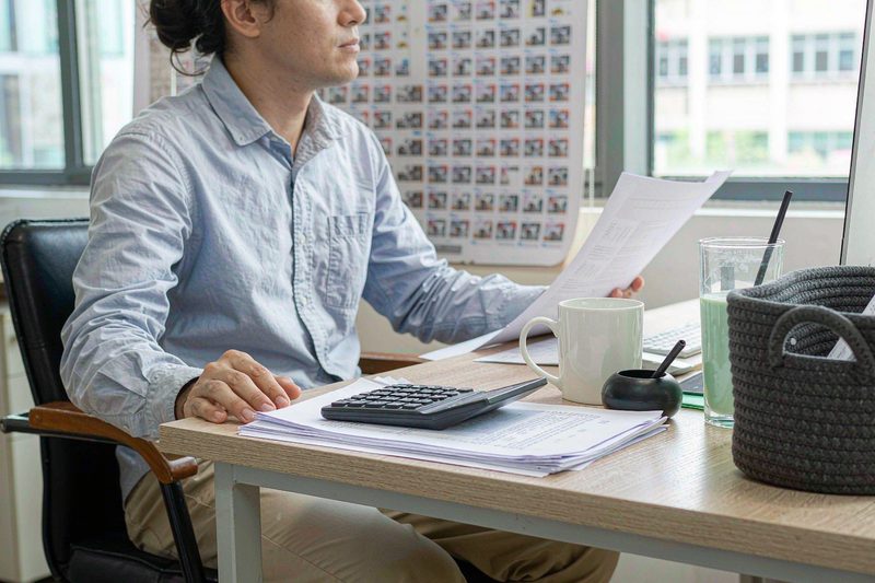 Home Consultant reviewing telecom line inventories and invoices at an office desk